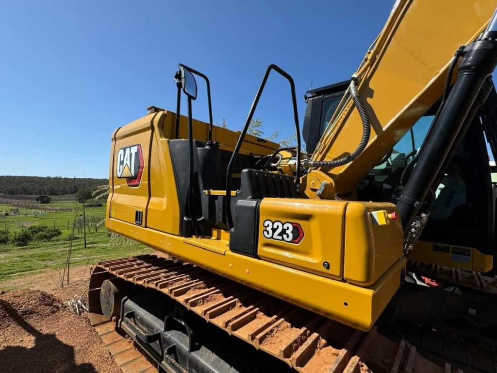 Rear view of the 2022 Caterpillar 323 Excavator with engine bonnet raised showing 323 model number decal and service access