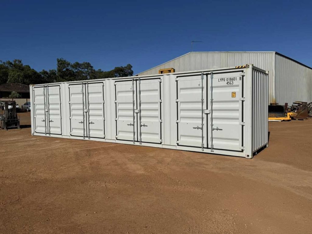 Side view of a white 40 foot shipping container on red dirt at Western Truck Sales yard with trees in the background