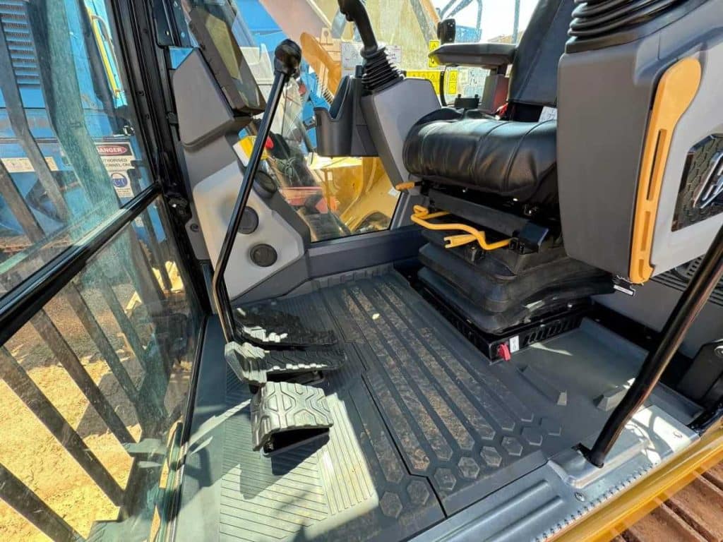 Operator seat and control layout inside the 2022 Cat 323 Excavator cab showing air-suspended seat armrests and monitor display