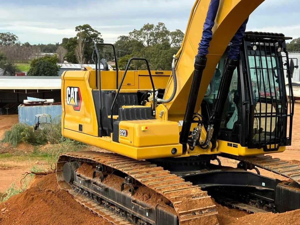 Close up of the 2022 Caterpillar 323 Excavator cab showing CAT branding and boom arm in as-new yellow paintwork