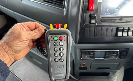 A close-up of a hand holding the wired electronic pendant remote control used to operate the tipper body.