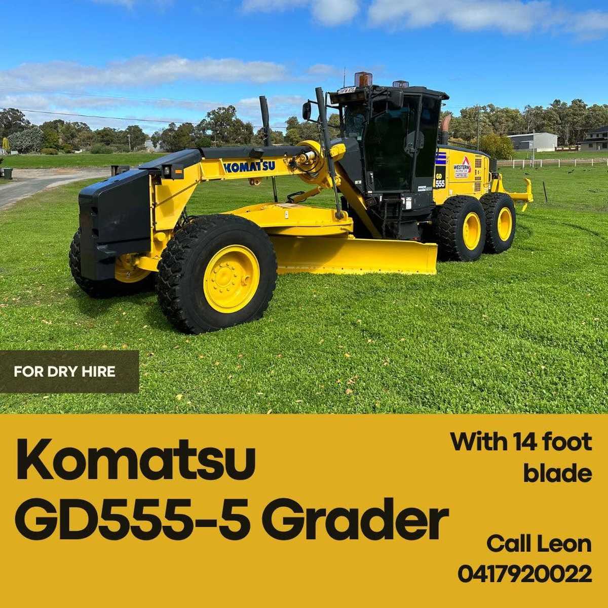A yellow Komatsu GD555-5 motor grader with a 14-foot blade parked on a grassy field, featured on a promotional banner for equipment dry hire.