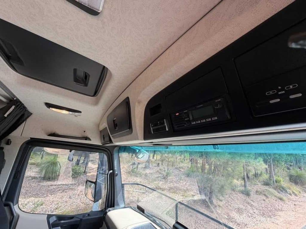 View looking up at the interior roof of the truck cab, detailing the overhead storage compartments and console