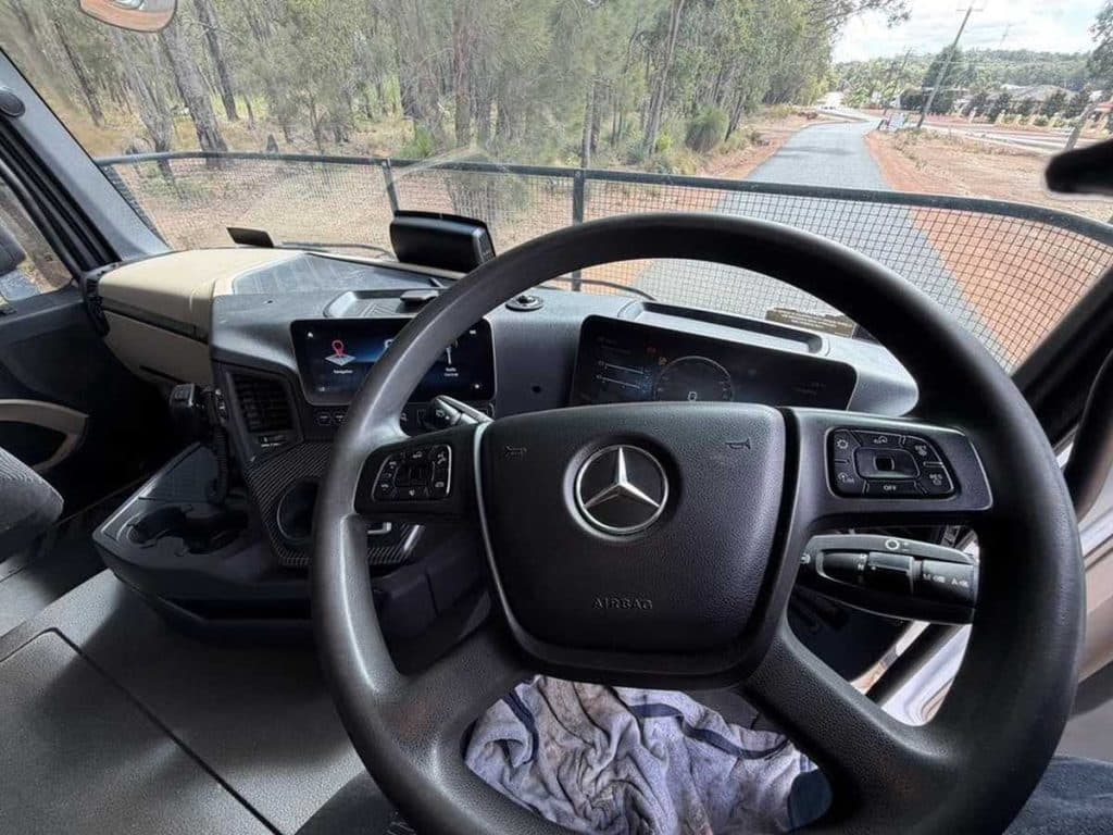 Interior view from the driver's seat focusing on the Mercedes-Benz branded steering wheel and digital dashboard