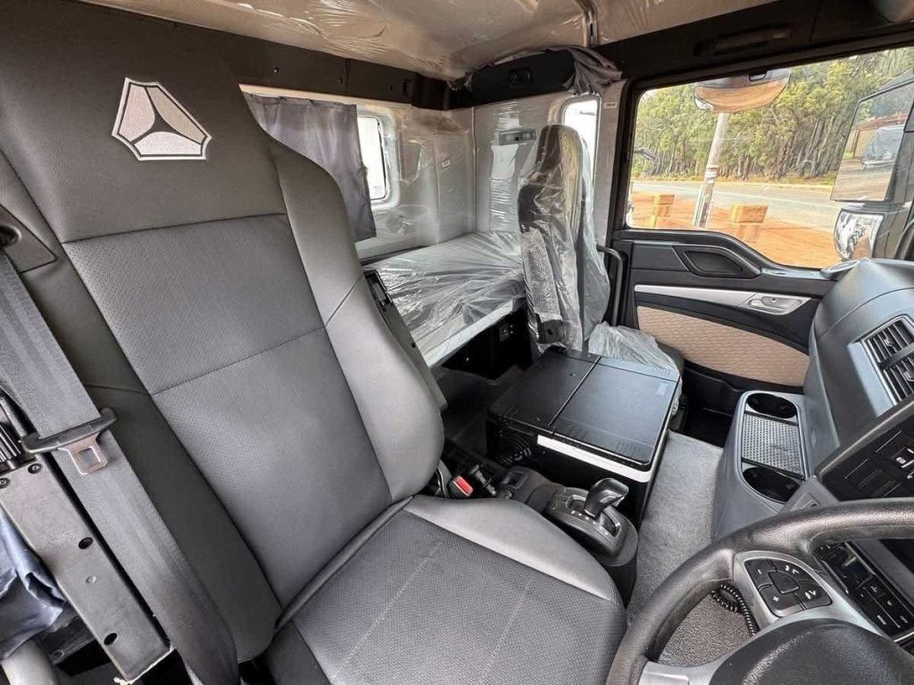 Detailed shot of the commercial truck cabin's black leather seat featuring the Sinotruk logo.