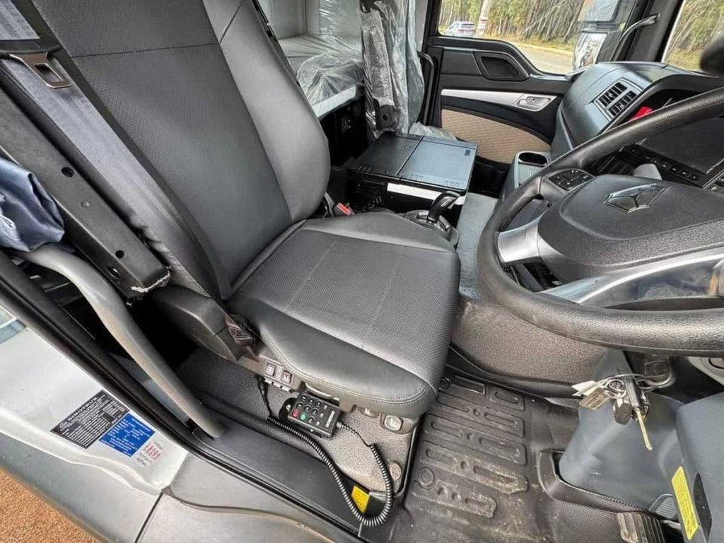 Interior view through an open door showing the driver's black vinyl seat and cab floor layout.