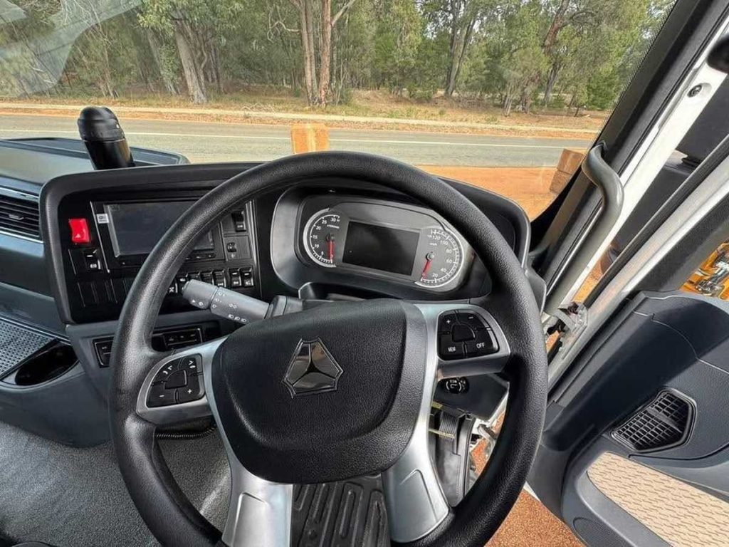 View from the driver's seat looking at the multi-function steering wheel featuring the Sitrak logo and instrument cluster