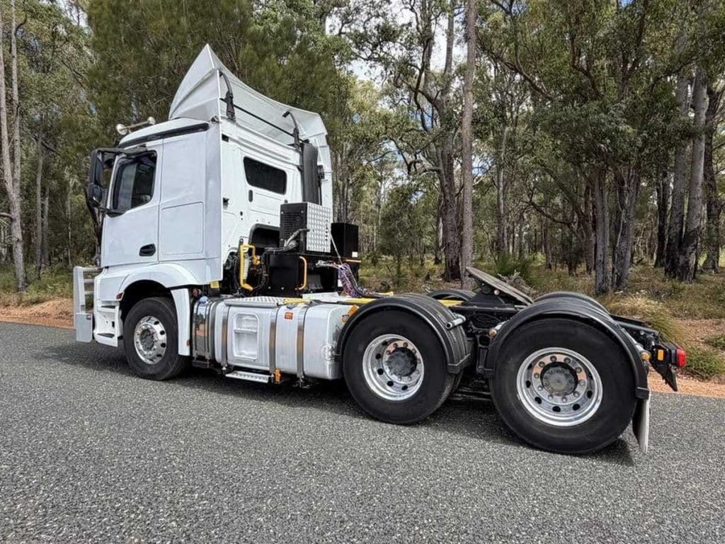 Rear three-quarter view of the truck chassis showing the dual rear axles and fifth wheel coupling.